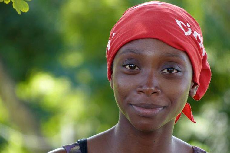 A young woman in a red headscarf, looking at the camera