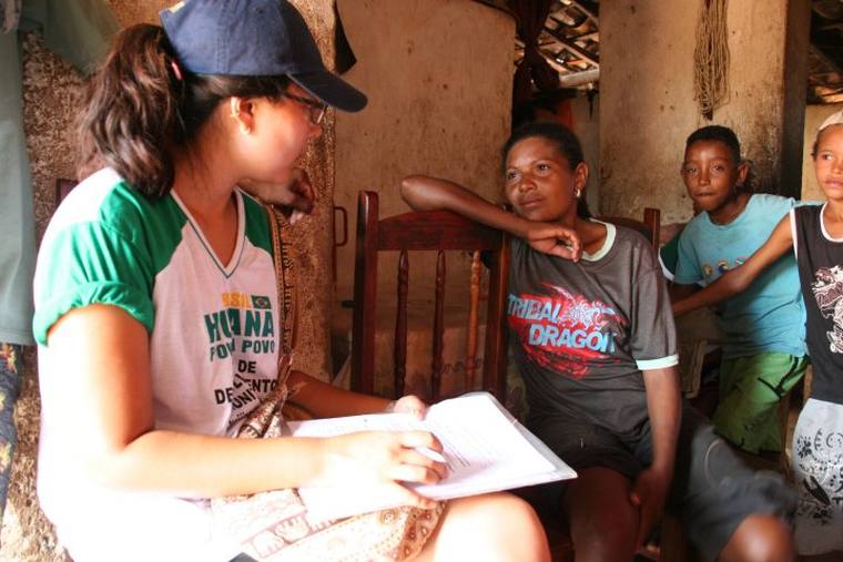 A volunteer sitting with a family in their home, taking notes