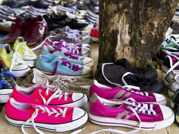 Rows of secondhand shoes laid out on boards beneath a tree, ready to find new owners.