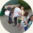 Schoolchildren carrying bags of clothing to a collection box