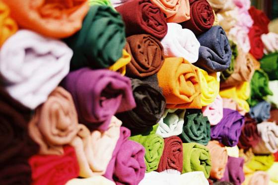 Rolled garments in many colours stacked closely together, ready to be redistributed.